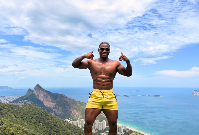 Athlete flexing on a mountain overlook above the coastline
